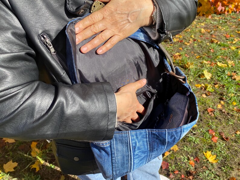 Upcycled denim messenger bag with striped design, adjustable strap, black nylon lining, and 2 interior pockets.