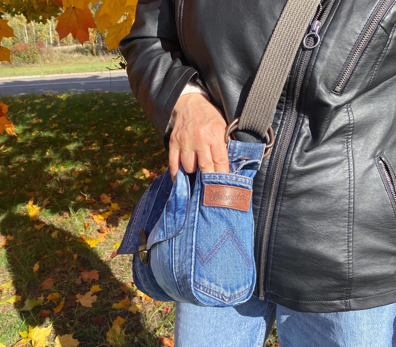 Upcycled denim messenger bag with striped design, adjustable strap, black nylon lining, and 2 interior pockets.