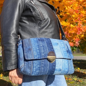 Upcycled denim messenger bag with striped design, adjustable strap, black nylon lining, and 2 interior pockets.