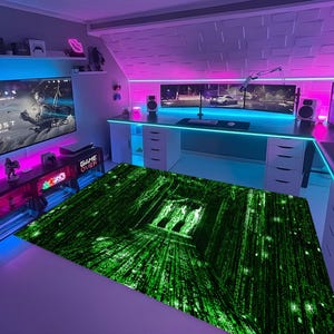 May include: A gaming room with a large green and black rug featuring a digital rain design. The room has a large screen displaying a video game, multiple monitors, and neon lighting. The words "GAME OVER" are visible on a console.