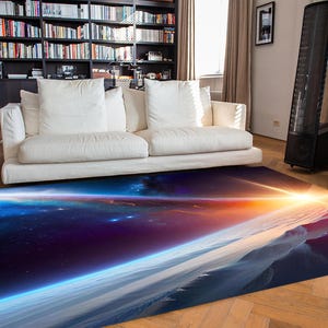 Peut inclure: Un tapis rectangulaire représentant une scène spatiale vibrante avec un soleil brillant et des corps célestes. Le design du tapis comprend des nuances de bleu, de violet, d'orange et de blanc, créant un paysage cosmique. Il est posé sur un parquet dans un salon.