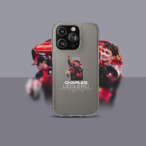 May include: A grey iPhone case with a clear back. The back features a photo of a race car driver in a red racing suit with the text "CHARLES LECLERC" printed below the photo.
