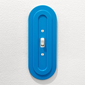 May include: A blue light switch with a white toggle in a rounded rectangular frame.