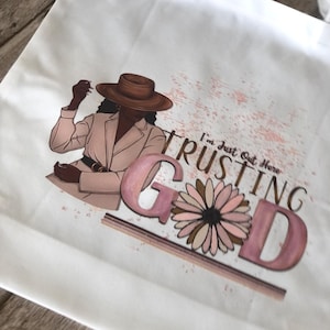 Trusting God Tote Bag, I’m Just Out Here Trusting God Tote, White Canvas Faith Bag, Pink & Tan Design, 13” Polyester Tote, Spiritual Gift