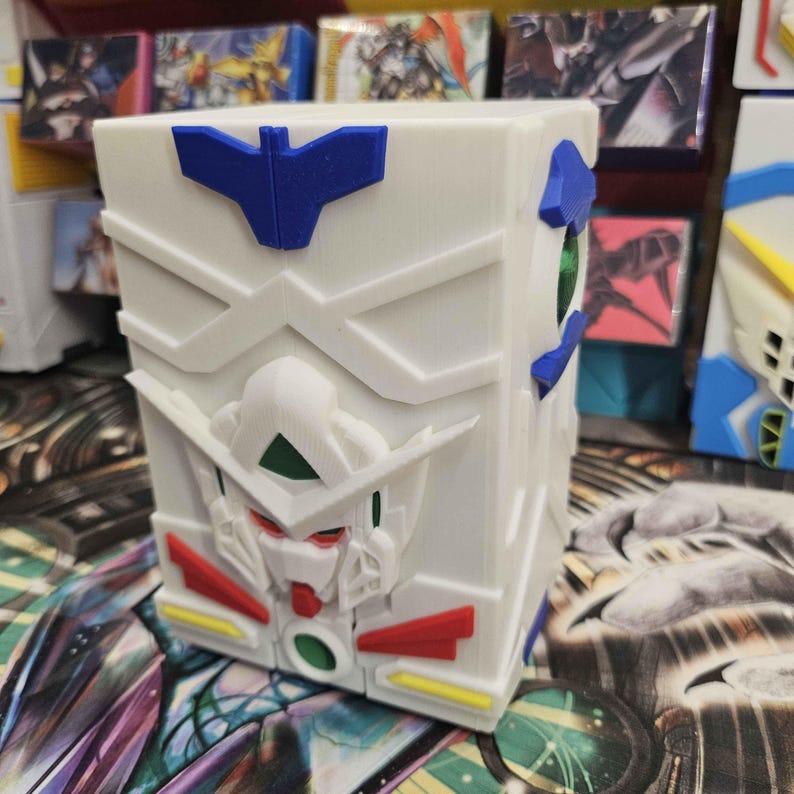 May include: A white rectangular storage box featuring a 3D relief of a robot head on the front. The design includes blue, red, and yellow accents, with a green circular detail at the base and a green eye-like element on the side panel of the box.
