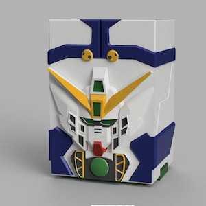 May include: A white, blue, yellow, and green box featuring a stylized robot face design. The box has a rectangular shape with a detailed, three-dimensional appearance. The robot face has a prominent green and red mouth, and yellow accents.