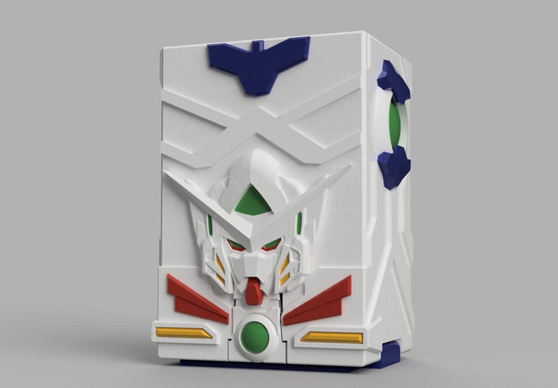 May include: A white rectangular storage box featuring a moulded relief of a robotic head on the front. The design includes blue, green, red, and yellow accents, with a prominent V-shaped crest on the forehead and a circular green emblem at the base.