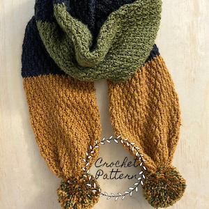 May include: A crocheted scarf with black, green, and orange stripes and pom-poms on the ends. The scarf is folded in half and the ends are tied together. The scarf is on a wooden surface. "Crochet Pattern" is written on a white circle with a green wreath around it.