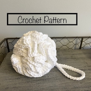 Può includere: Un pouf da bagno bianco all'uncinetto con un manico ad anello. Modello all'uncinetto.