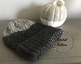 May include: A gray and black crocheted beanie hat with a cable stitch pattern. The hat is on a gray surface with a decorative pumpkin in the background. The text "Crochet Pattern" is written in a wreath.