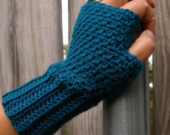 May include: Teal-colored fingerless gloves, hand-crocheted with a textured stitch. The gloves have a ribbed cuff and a thumb opening. The yarn appears to be a soft, medium-weight material, suitable for cooler weather. The gloves are shown on a person's hand.