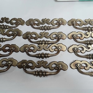 May include: A white ceramic mug with a black handle and the text "But First, Coffee" in a bold, black font. The mug is set against a blurred background, suggesting a cozy setting.