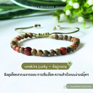 Puede incluir: Pulsera de cuentas con piedras Unakita y Jaspe Mookaite en tonos verdes, rojos y marrones. La pulsera tiene un cierre de nudo corredizo. El texto en la imagen dice "Unakite Lucky - หินถูกหวย". Fondo verde.