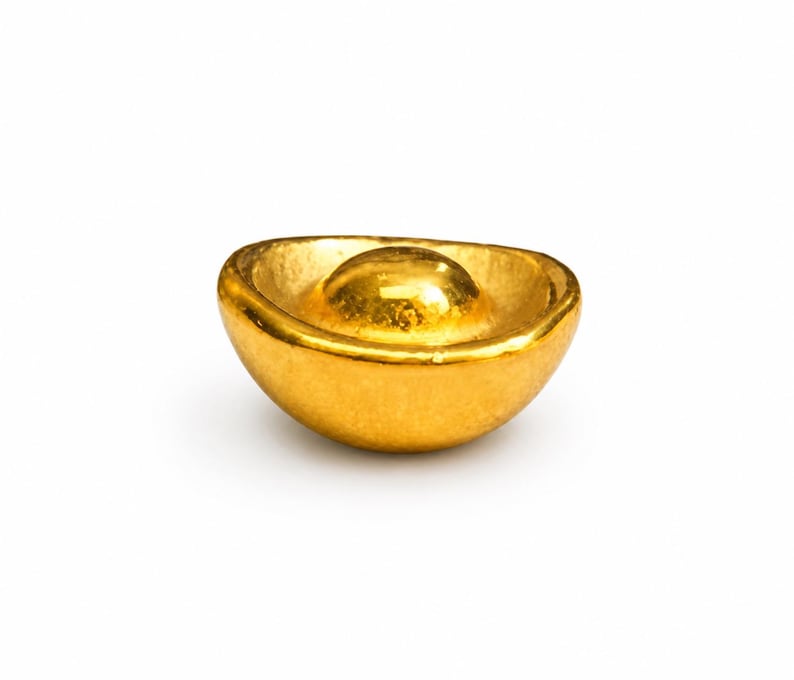 May include: A gold-colored ingot, a traditional symbol of wealth and prosperity. The ingot has a rounded shape with a raised central portion, and a smooth, reflective surface. The background is plain white.