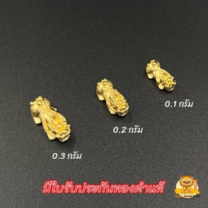 May include: Three small, gold-colored figurines of a mythical creature, each with intricate details. The figurines are labeled with weights of 0.1, 0.2, and 0.3 grams. The text in the image is in a foreign language.