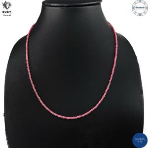Peut inclure: Un collier composé d'un seul rang de petites perles roses rondes et facettées. Le collier présente un agencement uniforme de ces pierres roses translucides enfilées ensemble pour former une forme circulaire continue sur un buste noir.