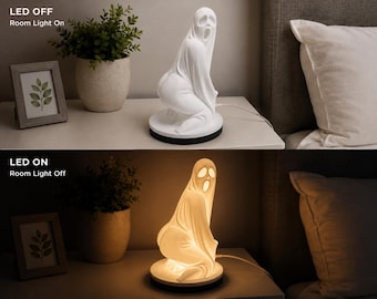 May include: A white ghost-shaped lamp featuring a figure in a draped sheet with a wide-mouthed expression. The lamp sits on a circular black base and includes a power cord. The image displays the lamp in two states: LED off and LED on.