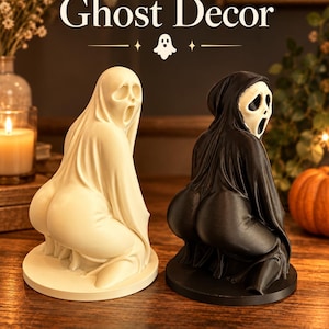 May include: Two ghost figurines, one white and one black, each featuring a hooded figure with a wide-mouthed expression and a curved posture. The text "Ghost Decor" is displayed above the figures, accompanied by a small ghost icon.