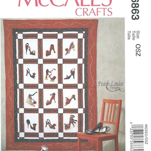 May include: A McCall's Crafts pattern for a quilt featuring various high-heeled shoe designs. The quilt has a red border, a black and white checkered pattern, and the text "McCall's Crafts". A red chair and shoes are next to the quilt.
