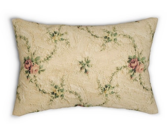 May include: Rectangular decorative pillow with a cream-colored background and a floral pattern. The pattern features pink roses, green leaves, and winding vines. The pillow has a textured appearance.