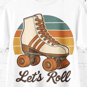 May include: White t-shirt with a vintage roller skate design in cream and orange, set against a sunset backdrop. The words "Let's Roll" are printed below the graphic. The t-shirt is displayed on a wooden hanger.