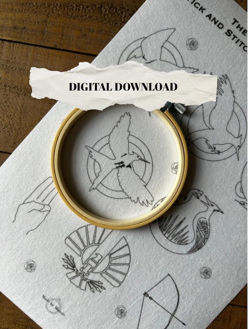May include: A wooden embroidery hoop holds a white fabric with a black bird design. The fabric is part of a larger piece with other black line art designs, including a hand gesture, a bow and arrow, and the text "DIGITAL DOWNLOAD".