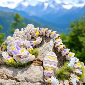 Könnte beinhalten: Eine bewegliche Drachenskulptur in Creme-, Gelb- und Lilatönen, die auf einem Felsen mit Bergkulisse platziert ist. Die Skulptur besteht aus mehreren Teilen und hat ein einzigartiges, künstlerisches Design mit verspielten Details.
