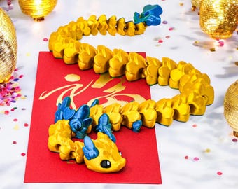 May include: A gold and blue segmented dragon toy on a red background with Chinese calligraphy. The dragon is curled up with its head facing the viewer.
