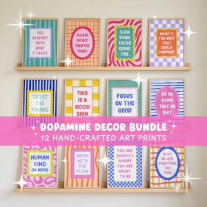 May include: Twelve rectangular art prints displayed on two wooden shelves, each featuring colorful patterns and motivational text. The prints include phrases like You Already Have What It Takes, Slow Down You're Doing Fine, and Do No Harm Take No Shit.