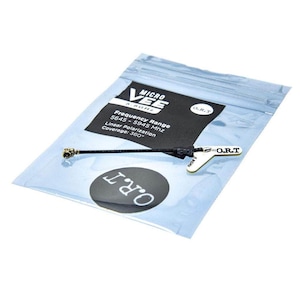 Op de afbeelding: Een zwarte antenne met een gouden connector en een wit label met de tekst "O.R.T" erop. De antenne zit in een doorzichtige plastic zak met de tekst "MICRO VEE 5.8GHz Frequency Range 5645-5945 Mhz Linear Polarization Coverage: 360°" erop gedrukt.