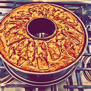 May include: A close-up of a round, golden-brown cake with a hole in the center, sitting on a black baking pan. The cake is on a black stovetop with a silver burner.