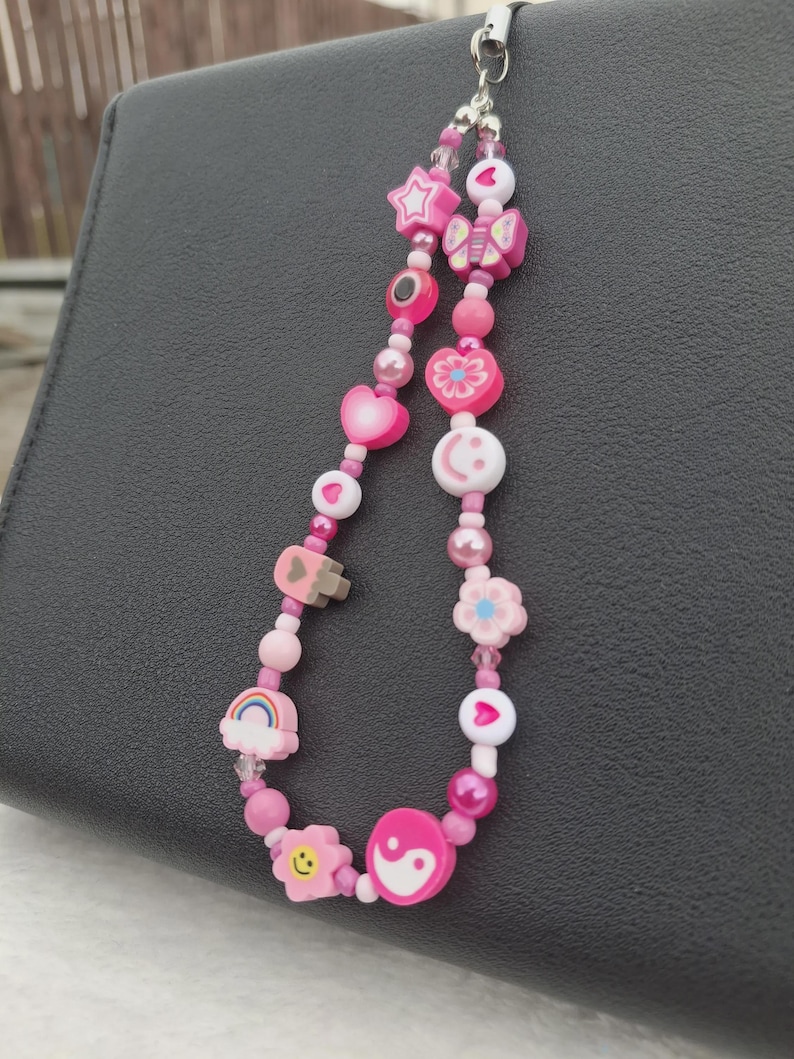 Handmade pink phone charm that is fully customisable. Each pink Y2K phone charm is made from upcycled pink beads, personalised with your name. Each custom phone charm is unique and makes a great gift for her, perfect for the Y2K trend. The pink phone straps are super cute and personalised, making a great Y2K phone accessory. The beaded pink phone wristlet is a great Y2K phone charm for any pink lover.