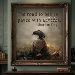May include: Framed artwork with a dark, gothic theme. The image features a raven perched on a rock, with skulls and a lantern in the foreground. Text reads: "The road to hell is paved with adverbs. -Stephen King."