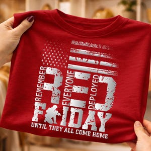 May include: A red t-shirt with a distressed white graphic design. The design includes an American flag, the words "REMEMBER EVERYONE DEPLOYED RED FRIDAY" and the phrase "UNTIL THEY ALL COME HOME."
