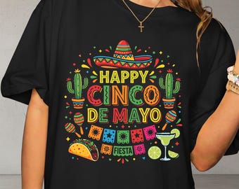 Può includere: T-shirt nero con un design colorato del Cinco de Mayo. La grafica include un sombrero, cactus, maracas, un taco e un margarita. Il testo recita "Happy Cinco de Mayo" e "Fiesta".