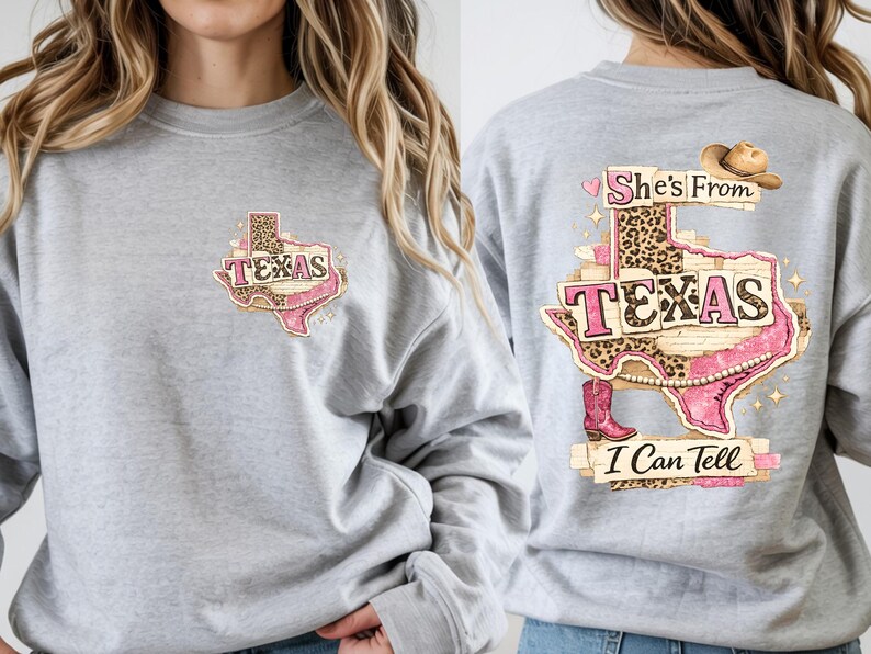 Może przedstawiać: Jasnoszara bluza z nadrukiem w kształcie Teksasu z napisem "TEXAS" w kolorze r&oacute;żowym i lamparcim. Tył bluzy zdobi większa grafika z napisem "She's From Texas I Can Tell", kapeluszem kowbojskim i butami.