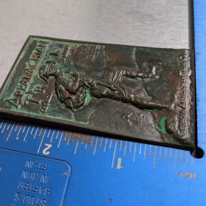 May include: A green metal plaque with the text "Appalachian Trail" and "The Georgia Appalachian Trail Club" embossed on it. The plaque features a raised image of a hiker carrying a backpack.