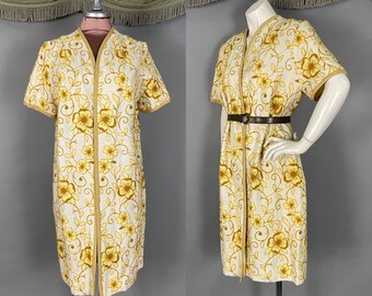 May include: A knee-length, open-front coat featuring short sleeves and a cream-coloured base with an all-over embroidered pattern of yellow and gold flowers and vines. The garment includes a tan trim along the edges and a dark brown belt.