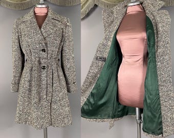 May include: A long-sleeved, knee-length coat featuring a textured black, white, and brown herringbone pattern. The coat has a notched lapel, a belted waist with two visible buttons, and a smooth, solid dark green lining visible on the interior.