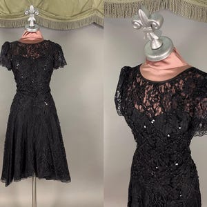 May include: A black lace dress with a fitted bodice and a full skirt. The dress is adorned with sequins and has short sleeves.