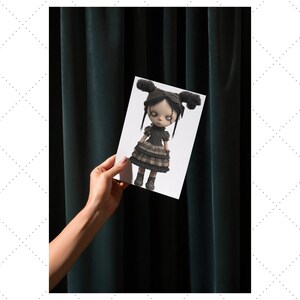 May include: A doll illustration on a white card held against a dark green curtain. The doll has black hair in two buns, a black dress, and grey boots. The doll's eyes are white with black details.
