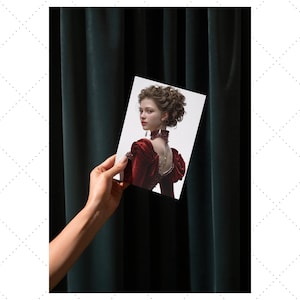 Pu&ograve; includere: Fotografia di una donna in abito rosso con colletto alto e maniche a sbuffo. L'immagine &egrave; tenuta in mano su uno sfondo di tenda verde scuro. La donna ha i capelli castani ricci e indossa una collana.