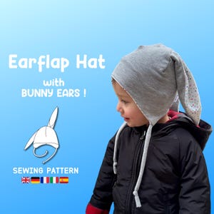 May include: A gray earflap hat with bunny ears, worn by a child. The hat has long, floppy ears with a polka dot pattern on the inside. The image includes the text "Earflap Hat with BUNNY EARS !" and "SEWING PATTERN".