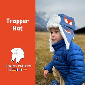 May include: A blue trapper hat with a white faux fur trim and a fox face design. The hat is being worn by a child in a blue jacket. The image includes the text "Trapper Hat" and "Sewing Pattern".