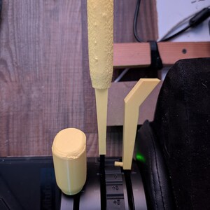 May include: A set of three yellow 3D-printed flight simulator controls. The set includes a textured handle, a cylindrical knob, and a lever. The controls are designed to be mounted on a black surface, with markings visible.