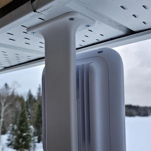 Puede incluir: Cámara de seguridad blanca montada en un soporte blanco unido a un alero blanco. La cámara está orientada hacia adelante y el soporte está orientado hacia un lado. La cámara está montada en el exterior de un edificio.