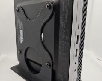 May include: A black desktop computer stand with a silver HP desktop computer attached. The stand has a circular cutout in the back and is secured to the computer with four screws.