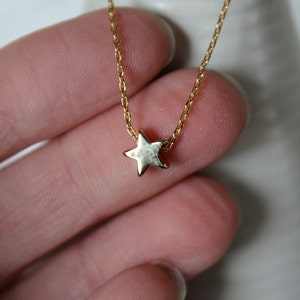 May include: A gold chain necklace with a small gold star pendant.