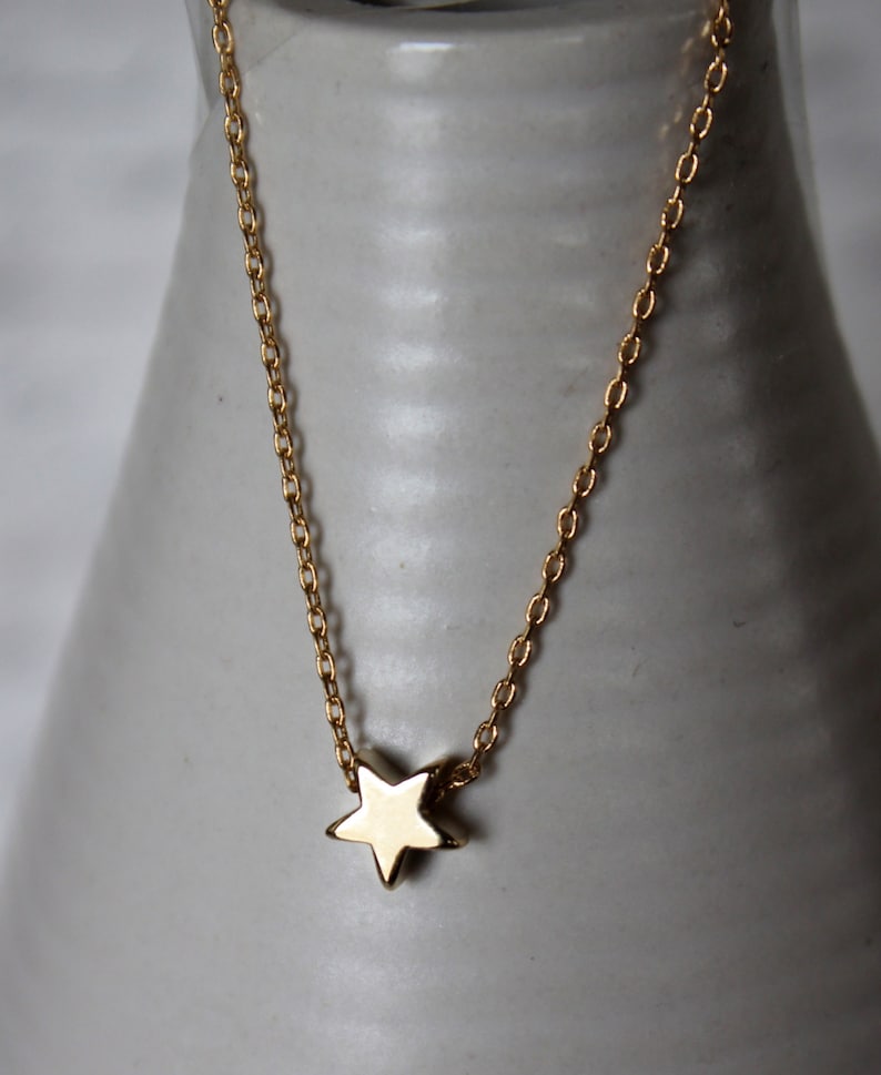 May include: A gold chain necklace with a small gold star pendant.