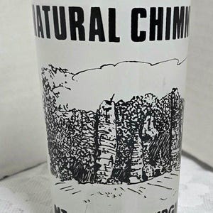 May include: A white glass with a black and white illustration of the Natural Chimneys in Mt. Solon, Virginia.